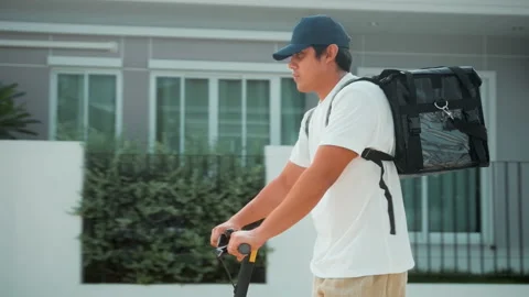 Smiling delivery man with thermal backpack riding on an electric scooter, del Видео 202204435