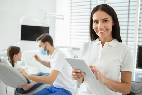 Smiling dentist working on digital tablet and looking at the camera with male Stock Photos