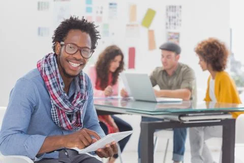 Smiling designer using his tablet pc and looking at camera Stock Photos