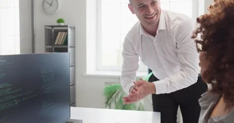 Smiling developer mentoring colleague while reviewing code at modern workstation Video stock 341835301