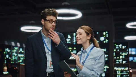 Smiling developers couple talking night datacenter closeup. Colleagues working Stock Photos