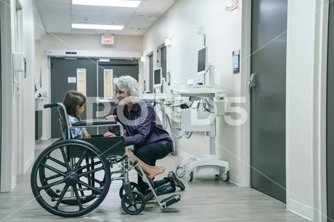 Smiling doctor comforting girl in wheelchair Stock Photos