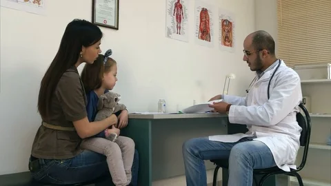 Smiling doctor explaining cardiogram to mother and little girl Stock Footage 72389429