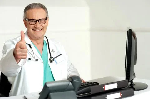 Smiling doctor gesturing thumbs up to camera Stock Photos