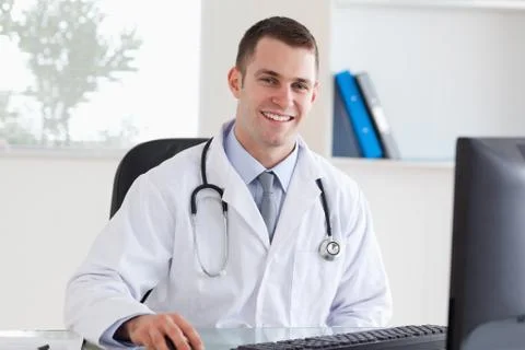 Smiling doctor on his computer Stock-Fotos