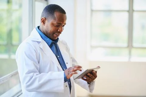 Smiling Doctor in Lab Coat Using Digital Tablet in Hospital Stock Photos