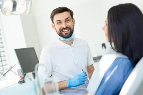 Smiling doctor looking at the camera and holding instruments for looking clie Stock Photos