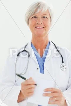 Smiling Doctor Pointing At Prescription Pad