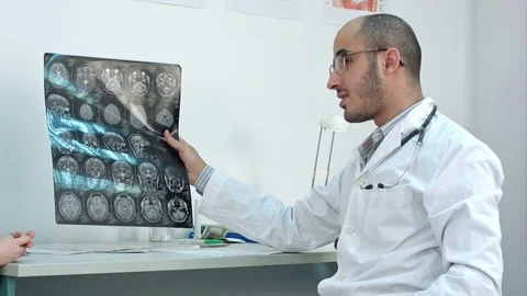 Smiling doctor showing brain computed tomography x-ray image to his patients Stock Footage 72369000
