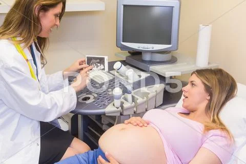 Smiling Doctor Showing Picture To The Smiling Pregnant Woman