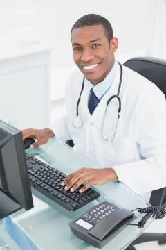 Smiling doctor using computer at medical office 스톡 사진