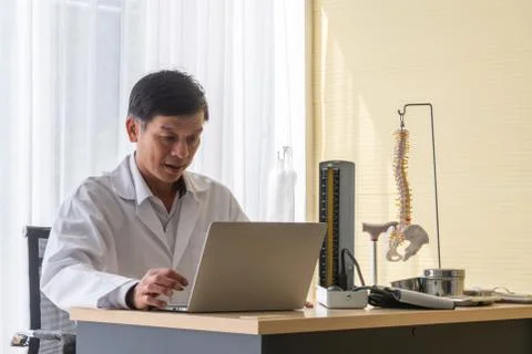 Smiling Doctor Using Laptop On Table Stock Photos