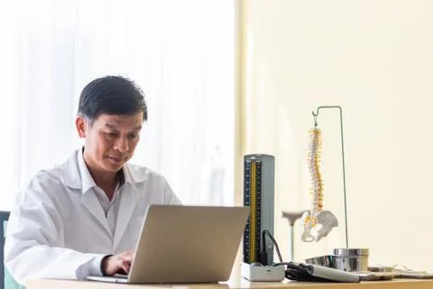 Smiling Doctor Using Laptop On Table Stock Photos