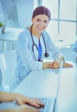 Smiling doctor using a laptop working with her colleagues in a bright hospital Stock Photos