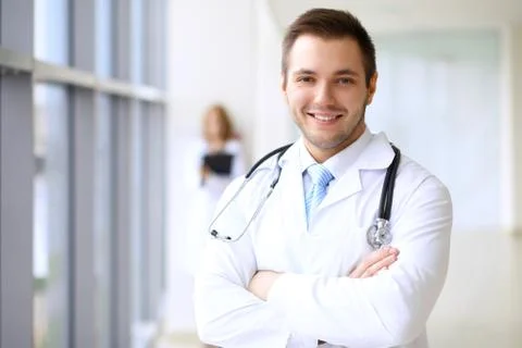 Smiling doctor waiting for his team while standing upright Stock-Fotos