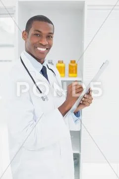 Smiling doctor writing a prescription in medical office Stock Photos