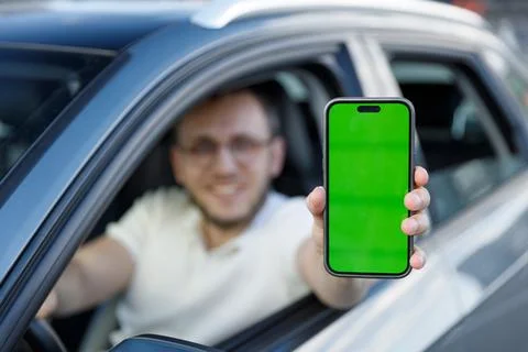 A Smiling Driver Displaying a Green Screen Smartphone from His Car Window Stock Photos
