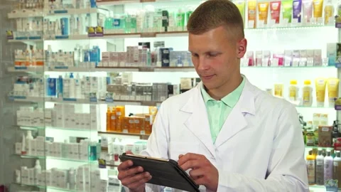 Smiling druggist using tablet in a vibrant pharmacy Stock Footage 311952015