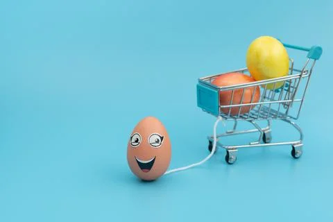 Smiling Easter egg with eyes is carrying blurred shopping trolley with decora Stock Photos