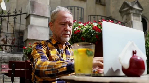 Smiling elderly bearded stylish man in cafe outside using laptop for 스톡 동영상 163715198