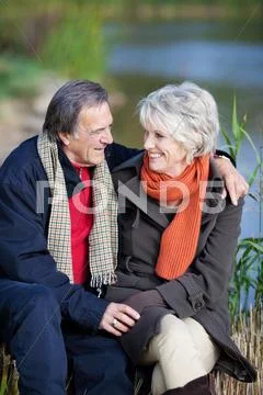 Smiling elderly couple on a lake shore Stock Photos