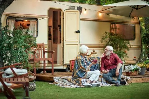 Smiling elderly couple sitting on the van porch and eating grapes Fotos Stock