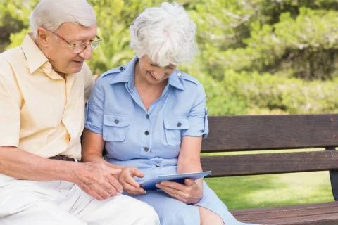 Smiling elderly couple using tablet in the park Foto stock