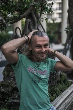 Smiling elderly man with long grey hair wearing green t-shirt Stock Photos