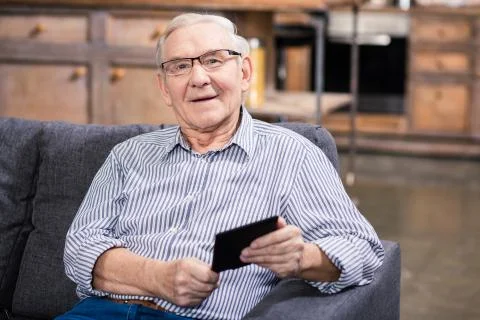 Smiling elderly man sitting on the couch Stock Photos