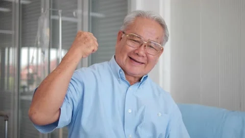 Smiling elderly patient Asian flexing muscles and looking at camera Stock Footage 149046190