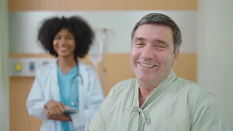 Smiling  elderly patient looking at camera with African American black doctor Stock Footage 196773873