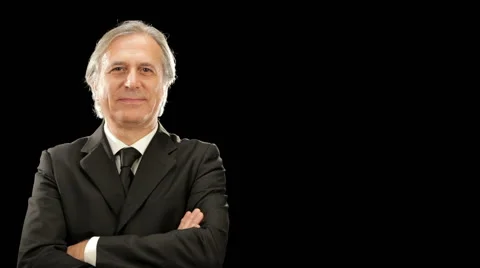 Smiling elegant businessman is looking at the camera isolated on black 動画素材 64478017