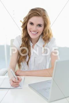 Smiling elegant businesswoman writing document at desk Stock Photos