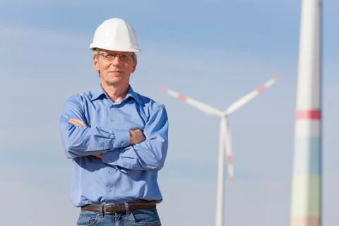 Smiling engineer with hard hat  in front of a windmill Stock Photos
