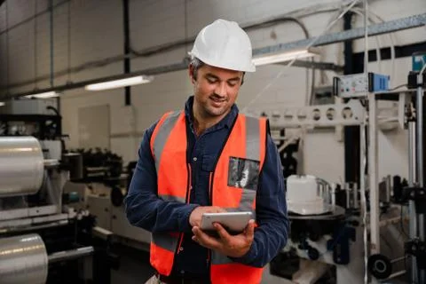 Smiling engineer holding tablet standing in factory Stock Photos