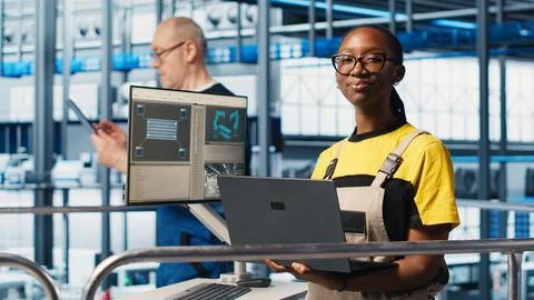 Smiling engineer overseeing smart factory, looking at collected data on laptop Stock Photos