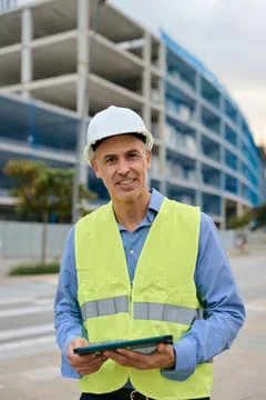 Smiling engineer supervising construction site holding tablet Stock Photos