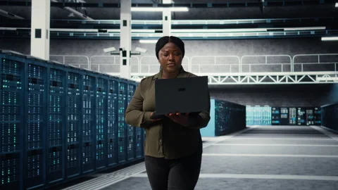 Smiling engineer walking in data center with laptop, checking hardware Stock Footage 317126301