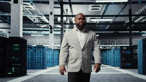 Smiling engineer walking in data center, checking hardware for system stability Stock Photos