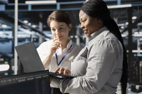 Smiling engineering team using laptop in data center, running scripts Stock Photos