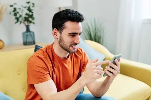 Smiling ethnic man using smartphone at home Stock Photos