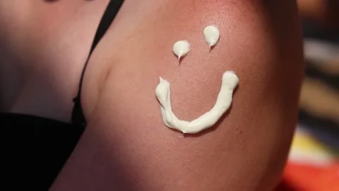 Smiling face design with sunscreen on a woman's shoulder Stock Footage 313551702