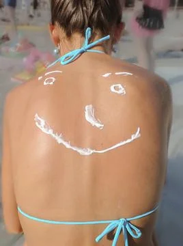 Smiling face drawn with sunscreen on the back Stock Photos