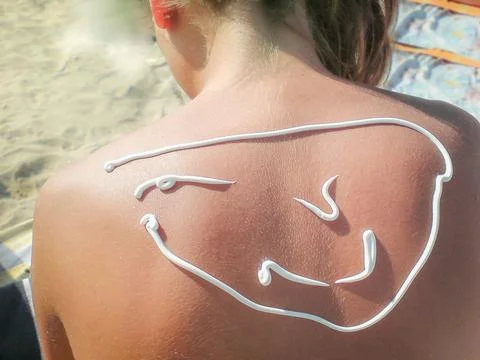 Smiling face drawn with sunscreen on the back Stock Photos