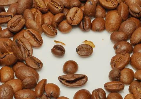 A smiling face  made of coffee beans on a white background Stock Photos