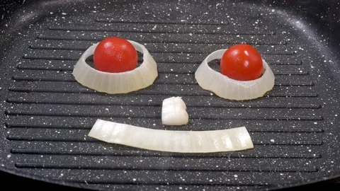 Smiling face of onions and cherry tomatoes in a pan Stock-Footage 88257965