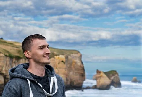 The smiling face of a young man on a background of sky, mountains and sea Stock Photos