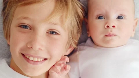 Smiling faces of the brothers, top view.  Happy newborn baby with his brother Stock Footage 165392298