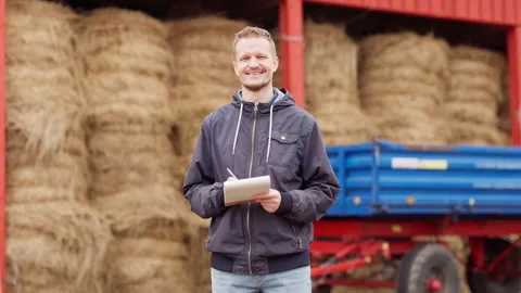 Smiling farmer with notepad posing at hay bales storage Stock Footage 161192470