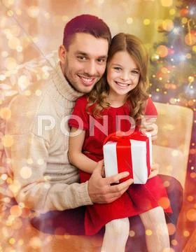 Smiling father and daughter holding gift box Stock Photos